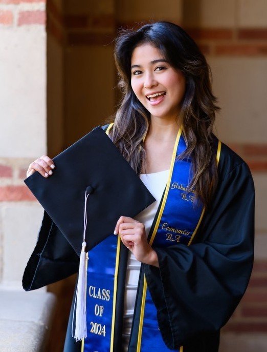 Smiling graduate in cap and gown holding a diploma